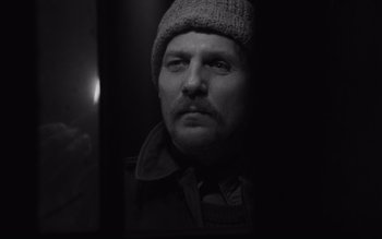 Movie still from “Satantango” (1994), directed by Béla Tarr – A black and white photo of a man wearing a hat; Close Up shot, Low angle