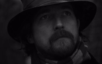 Movie still from “Satantango” (1994), directed by Béla Tarr – A person wearing a hat; Close Up shot, Low angle
