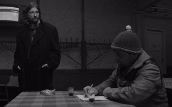 Movie still from “Satantango” (1994), directed by Béla Tarr – Two men sitting at a table writing on papers; Medium shot, Over the shoulder angle