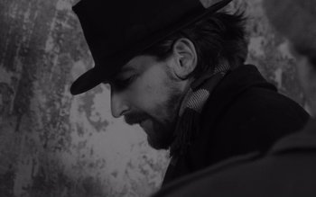 Movie still from “Satantango” (1994), directed by Béla Tarr – A black and white photo of a man in a hat; Close Up shot, Low angle
