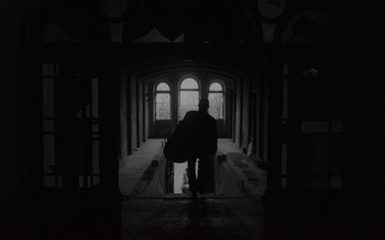 Movie still from “Satantango” (1994), directed by Béla Tarr – A man walking down a hallway with a suitcase; Wide shot, Low angle