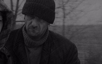 Movie still from “Satantango” (1994), directed by Béla Tarr – A black and white photo of a man wearing a hat; Close Up shot, Low angle
