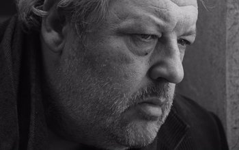 Movie still from “Satantango” (1994), directed by Béla Tarr – Black and white photograph of an older man's face; Close Up shot, Low angle