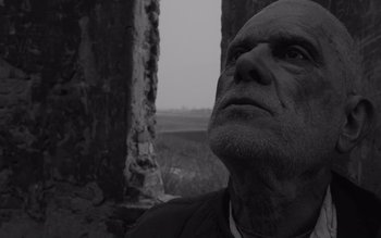 Movie still from “Satantango” (1994), directed by Béla Tarr – An older man looking up into the sky; Close Up shot, Low angle