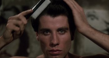Movie still from “Saturday Night Fever” (1977), directed by John Badham – A man combing his hair with a brush; Close Up shot, Low angle