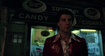 Movie still from “Saturday Night Fever” (1977), directed by John Badham – A man in a red jacket standing in front of a candy store; Medium shot, Low angle