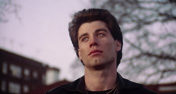 Movie still from “Saturday Night Fever” (1977), directed by John Badham – A person wearing a black shirt; Close Up shot, Low angle
