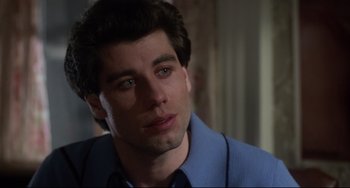 Movie still from “Saturday Night Fever” (1977), directed by John Badham – A person wearing a suit and tie; Close Up shot, Over the shoulder angle