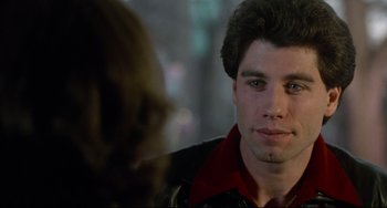 Movie still from “Saturday Night Fever” (1977), directed by John Badham – A man in a leather jacket looking at a woman in a red shirt; Close Up shot, Over the shoulder angle