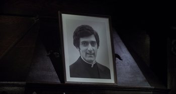 Movie still from “Saturday Night Fever” (1977), directed by John Badham – An old photo of a man in a priest's outfit; Close Up shot, Low angle