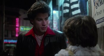 Movie still from “Saturday Night Fever” (1977), directed by John Badham – A man in a red and black jacket talking to a woman in a black jacket; Close Up shot, Over the shoulder angle