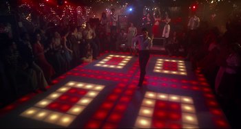Movie still from “Saturday Night Fever” (1977), directed by John Badham – A group of people standing around a dance floor; Extreme Wide shot, High angle
