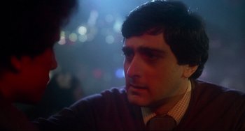 Movie still from “Saturday Night Fever” (1977), directed by John Badham – A person wearing a neck tie; Close Up shot, Over the shoulder angle