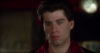 Movie still from “Saturday Night Fever” (1977), directed by John Badham – A man with a red shirt is looking to his left; Close Up shot, Low angle