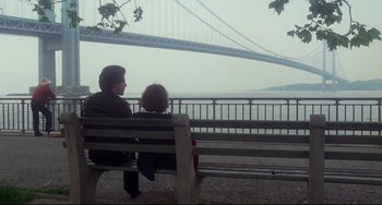 Movie still from “Saturday Night Fever” (1977), directed by John Badham – Two people sitting on a bench looking out at a bridge; Wide shot, Over the shoulder angle