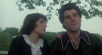 Movie still from “Saturday Night Fever” (1977), directed by John Badham – A man and a woman standing next to each other in front of a tree; Close Up shot, Low angle