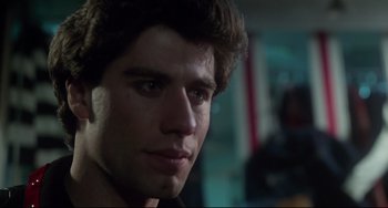 Movie still from “Saturday Night Fever” (1977), directed by John Badham – A young man's face in a dark room; Close Up shot, Low angle