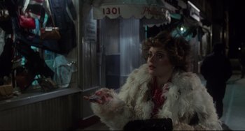 Movie still from “Saturday Night Fever” (1977), directed by John Badham – A woman in a white fur coat holding a cell phone; Medium shot, Over the shoulder angle