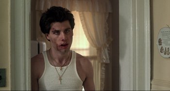 Movie still from “Saturday Night Fever” (1977), directed by John Badham – A young man in a white tank top looking into a mirror; Medium shot, Over the shoulder angle