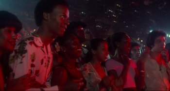 Movie still from “Saturday Night Fever” (1977), directed by John Badham – A group of people standing in front of a stage; Medium shot, Low angle