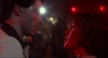Movie still from “Saturday Night Fever” (1977), directed by John Badham – A man and a woman face to face in front of lights; Close Up shot, Low angle