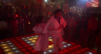 Movie still from “Saturday Night Fever” (1977), directed by John Badham – A couple of people that are dancing on a dance floor; Wide shot, Low angle