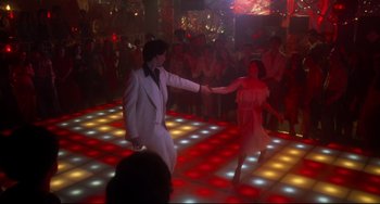 Movie still from “Saturday Night Fever” (1977), directed by John Badham – A couple of people that are dancing on a dance floor; Wide shot, High angle
