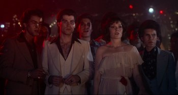 Movie still from “Saturday Night Fever” (1977), directed by John Badham – A man and a woman standing next to each other; Medium shot, Low angle