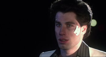 Movie still from “Saturday Night Fever” (1977), directed by John Badham – A man with a bandage on his face; Close Up shot, Low angle