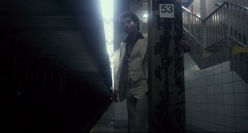 Movie still from “Saturday Night Fever” (1977), directed by John Badham – A man in a suit standing next to a wall; Wide shot, Low angle