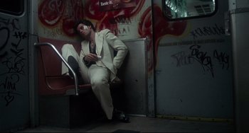 Movie still from “Saturday Night Fever” (1977), directed by John Badham – A man sitting on a bench with a cell phone in his hand; Wide shot, High angle