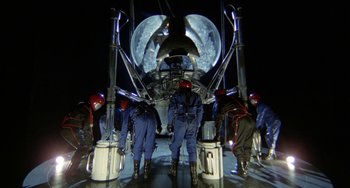Movie still from “Saturn 3” (1980), directed by John Barry – A group of men standing next to each other in front of a space ship; Wide shot, Low angle