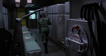 Movie still from “Saturn 3” (1980), directed by John Barry – A man in a green suit walking down a hallway; Wide shot, High angle