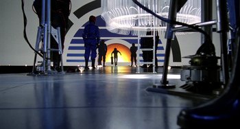 Movie still from “Saturn 3” (1980), directed by John Barry – A group of people standing in front of an orange light; Extreme Wide shot, Low angle
