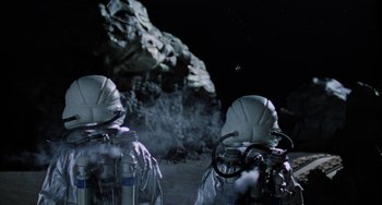 Movie still from “Saturn 3” (1980), directed by John Barry – Two astronauts in spacesuits on the surface of an asteroid; Medium shot, Low angle