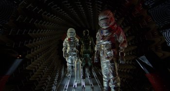 Movie still from “Saturn 3” (1980), directed by John Barry – A group of people in a room with a lot of lights on them; Wide shot, Overhead angle