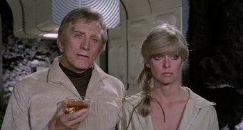 Movie still from “Saturn 3” (1980), directed by John Barry – A man and a woman standing next to each other holding a drink; Close Up shot, Low angle