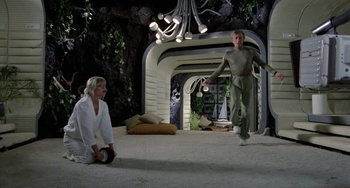 Movie still from “Saturn 3” (1980), directed by John Barry – Two people in a room with lights on the ceiling; Wide shot, Low angle