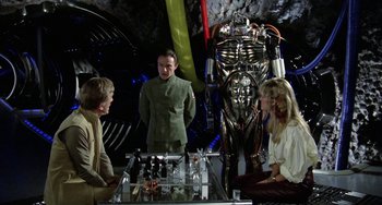 Movie still from “Saturn 3” (1980), directed by John Barry – A group of people sitting around a table; Medium shot, Over the shoulder angle