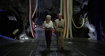 Movie still from “Saturn 3” (1980), directed by John Barry – A man and a woman are walking through a tunnel; Wide shot, Low angle