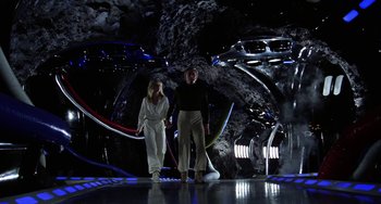 Movie still from “Saturn 3” (1980), directed by John Barry – Two people standing in a dark room with lights on; Wide shot, Low angle