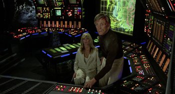 Movie still from “Saturn 3” (1980), directed by John Barry – A man and a woman are sitting in a control room; Medium shot, High angle