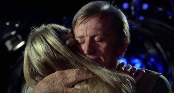 Movie still from “Saturn 3” (1980), directed by John Barry – An older man hugging a younger woman in front of a blue background; Close Up shot, Over the shoulder angle
