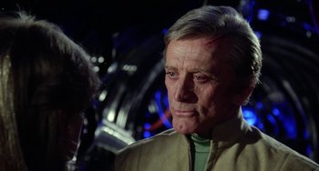Movie still from “Saturn 3” (1980), directed by John Barry – An older man in a tan jacket looking at the camera; Close Up shot, Over the shoulder angle