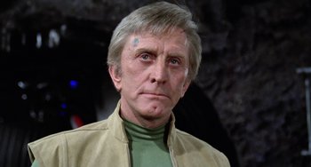 Movie still from “Saturn 3” (1980), directed by John Barry – An older man wearing a green shirt and a tan jacket; Close Up shot, Low angle