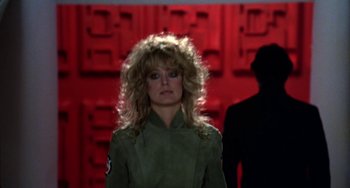 Movie still from “Saturn 3” (1980), directed by John Barry – A woman in a military uniform standing in front of a wall; Close Up shot, Over the shoulder angle