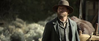 Movie still from “Godless” (2017), directed by Scott Frank – A man wearing a hat and a suit; Medium shot, Low angle