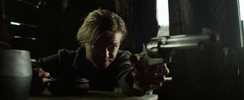 Movie still from “Godless” (2017), directed by Scott Frank – A man holding a gun in a dark room; Close Up shot, Low angle