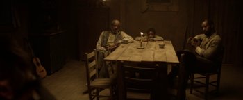 Movie still from “Godless” (2017), directed by Scott Frank – Two people sitting at a table with a lit candle in the middle; Wide shot, High angle