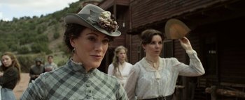 Movie still from “Godless” (2017), directed by Scott Frank – A woman in an old fashioned hat standing in front of two other women; Close Up shot, Over the shoulder angle
